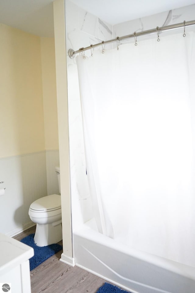 bathroom with toilet, wood finished floors, and shower / tub combo