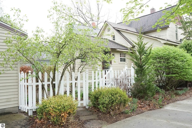 view of property exterior with fence, a shingled roof, and a chimney