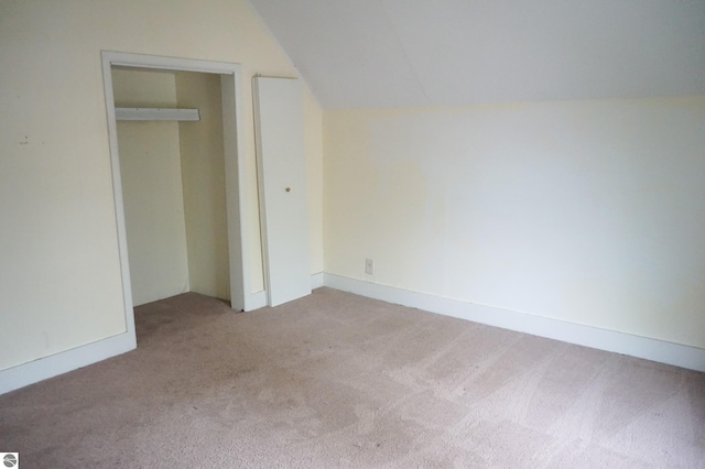 unfurnished bedroom featuring light colored carpet, lofted ceiling, and a closet