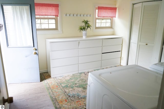 bedroom with washer / dryer, multiple windows, wood finished floors, and a closet