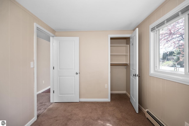9869 E Cherry Bend Rd, Traverse City, MI 49684 - unfurnished bedroom featuring a baseboard heating unit, carpet flooring, a walk in closet, and a closet