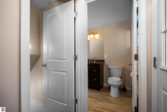9869 E Cherry Bend Rd, Traverse City, MI 49684 - half bathroom featuring wood finished floors, vanity, toilet, and baseboards