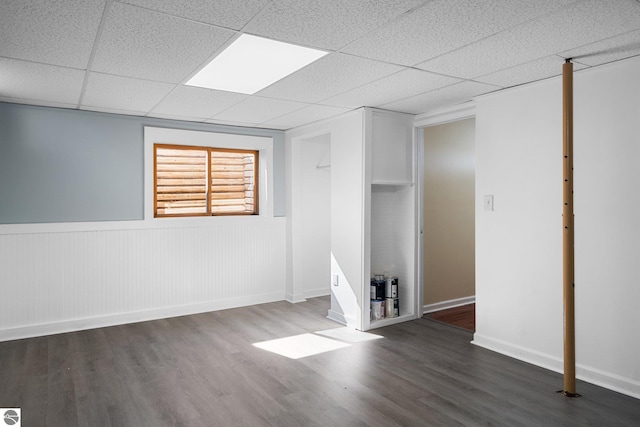 9869 E Cherry Bend Rd, Traverse City, MI 49684 - empty room with wood finished floors, a paneled ceiling, a wainscoted wall, and baseboards
