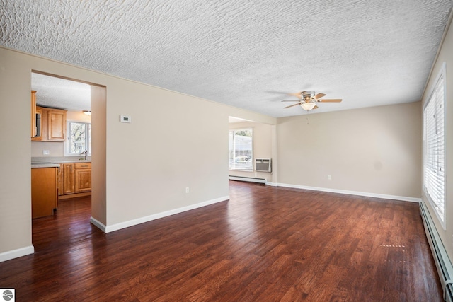 9869 E Cherry Bend Rd, Traverse City, MI 49684 - unfurnished living room featuring a baseboard heating unit, a ceiling fan, dark wood-type flooring, baseboard heating, and a textured ceiling