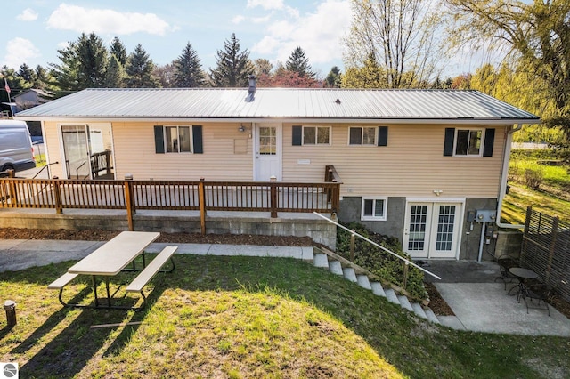 9869 E Cherry Bend Rd, Traverse City, MI 49684 - rear view of house with a yard, a patio, metal roof, and a wooden deck