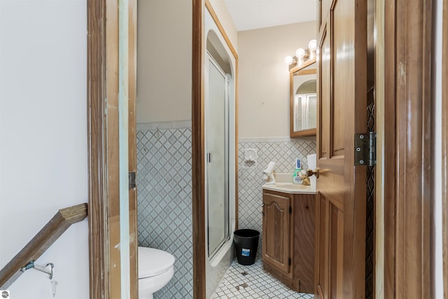 8377 Zosel St, Onekama, MI 49675 - bathroom featuring tile walls, tile patterned flooring, toilet, a shower stall, and a wainscoted wall