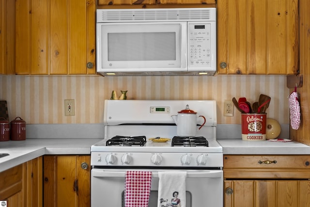 66 N Center St, Lake City, MI 49651 - kitchen featuring white appliances, wallpapered walls, light countertops, and brown cabinets
