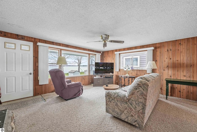 8805 Iroquois Trl, Saint Helen, MI 48656 - living room featuring carpet flooring, wooden walls, ceiling fan, and a textured ceiling