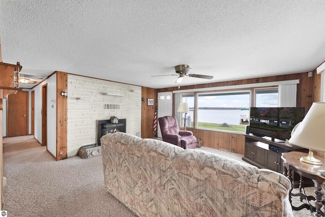 8805 Iroquois Trl, Saint Helen, MI 48656 - living area featuring wood walls, light carpet, a fireplace, a textured ceiling, and a ceiling fan