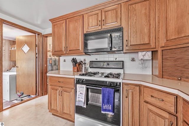 8805 Iroquois Trl, Saint Helen, MI 48656 - kitchen with black microwave, gas range, washer / dryer, and light countertops