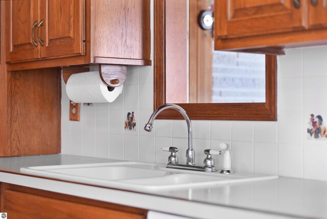 8805 Iroquois Trl, Saint Helen, MI 48656 - kitchen view of tasteful backsplash, light countertops, brown cabinetry, and a sink
