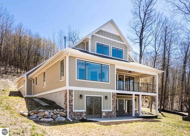 3046 E Greenwood Rd, Lake Leelanau, MI 49653 - rear view of house with a balcony, board and batten siding, french doors, stone siding, and a yard