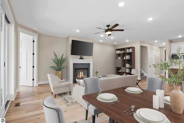3046 E Greenwood Rd, Lake Leelanau, MI 49653 - dining area featuring a ceiling fan, baseboards, a glass covered fireplace, light wood finished floors, and recessed lighting
