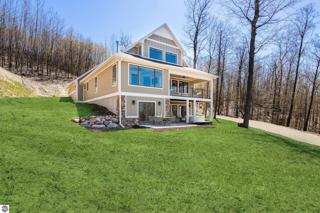 3046 E Greenwood Rd, Lake Leelanau, MI 49653 - back of property featuring a lawn, a patio, a balcony, board and batten siding, and a ceiling fan