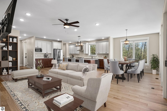 3046 E Greenwood Rd, Lake Leelanau, MI 49653 - living room with light wood-style floors, ceiling fan, a chandelier, recessed lighting, and baseboards