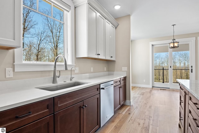 3046 E Greenwood Rd, Lake Leelanau, MI 49653 - kitchen featuring dishwasher, a sink, light countertops, light wood-style floors, and pendant lighting