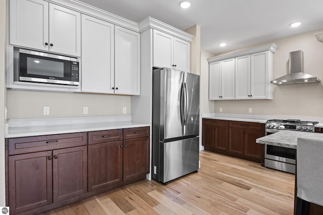 3046 E Greenwood Rd, Lake Leelanau, MI 49653 - kitchen with appliances with stainless steel finishes, wall chimney exhaust hood, light countertops, light wood-style floors, and recessed lighting