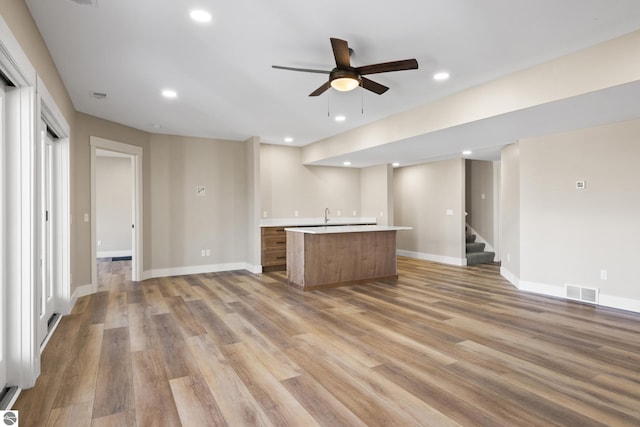 3046 E Greenwood Rd, Lake Leelanau, MI 49653 - kitchen with open floor plan, a kitchen island with sink, light countertops, ceiling fan, and light wood-style flooring