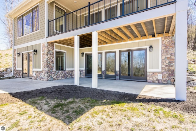 3046 E Greenwood Rd, Lake Leelanau, MI 49653 - back of property featuring board and batten siding, stone siding, a patio area, and french doors