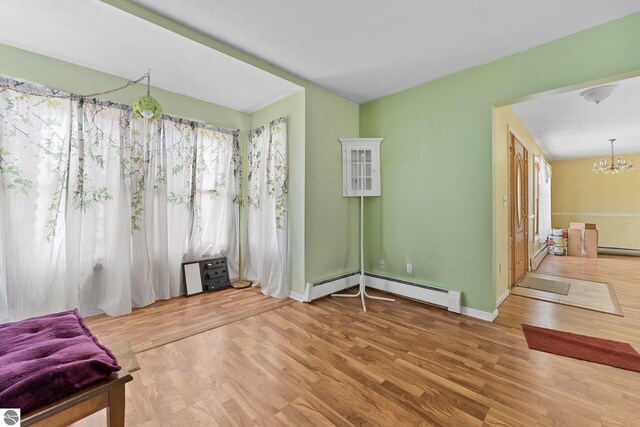 512 NW Kalkaska St, Kalkaska, MI 49646 - unfurnished living room featuring a chandelier, wood finished floors, a baseboard radiator, and baseboards