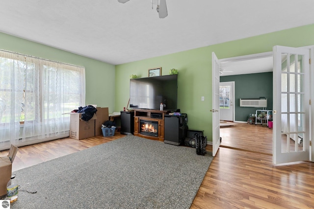 512 NW Kalkaska St, Kalkaska, MI 49646 - living area with a ceiling fan, wood finished floors, an AC wall unit, a glass covered fireplace, and baseboard heating