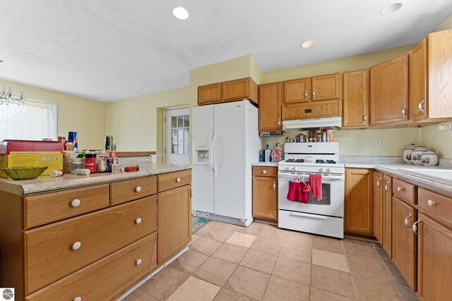 512 NW Kalkaska St, Kalkaska, MI 49646 - kitchen with white appliances, under cabinet range hood, light countertops, recessed lighting, and brown cabinets
