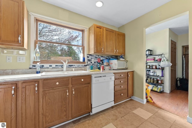 512 NW Kalkaska St, Kalkaska, MI 49646 - kitchen featuring white appliances, a sink, light countertops, backsplash, and brown cabinets