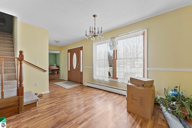 512 NW Kalkaska St, Kalkaska, MI 49646 - entrance foyer featuring a baseboard heating unit, stairway, wood finished floors, a chandelier, and baseboards