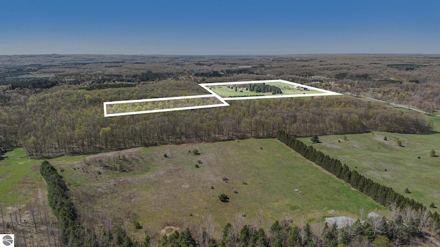 aerial view of property and surrounding area featuring property parcel outlined, a heavily wooded area, and rural landscape