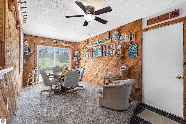 dining room with wood walls, a textured ceiling, and a ceiling fan