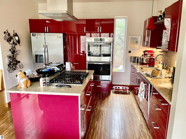 kitchen featuring under cabinet range hood, appliances with stainless steel finishes, a sink, dark wood-type flooring, and red cabinets