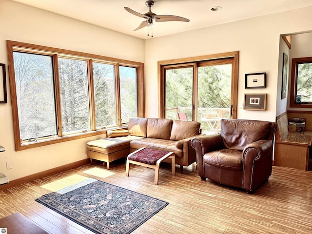 living room featuring a ceiling fan, healthy amount of natural light, light wood-style flooring, and baseboards