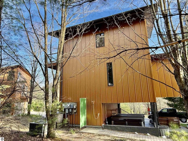 view of property exterior featuring a covered hot tub and central AC