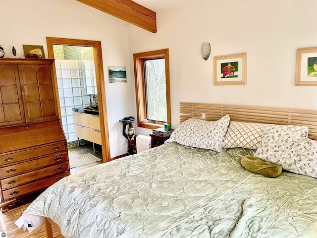 bedroom with beamed ceiling, wood finished floors, and connected bathroom