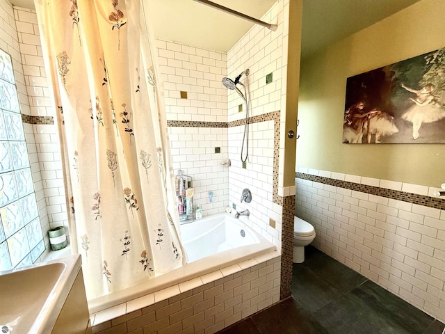 bathroom featuring tile patterned floors, tile walls, tiled shower / bath combo, toilet, and wainscoting