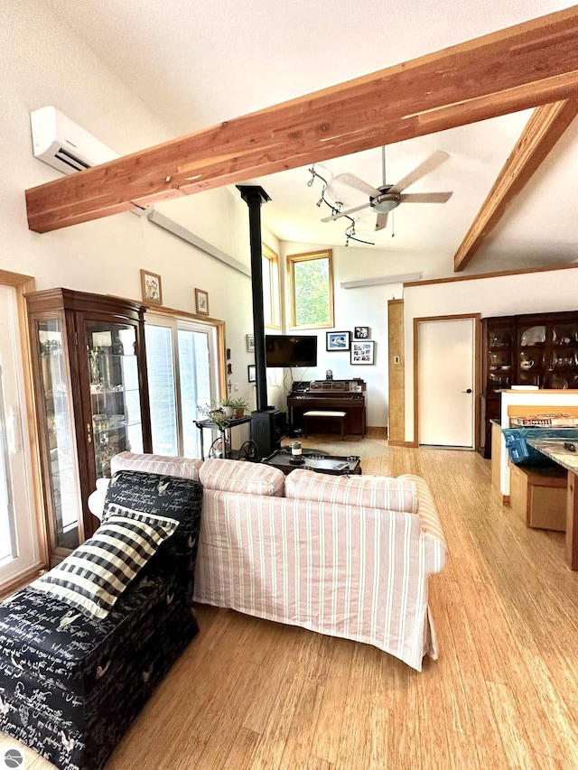 living room with a wall mounted air conditioner, wood finished floors, ceiling fan, and a wood stove