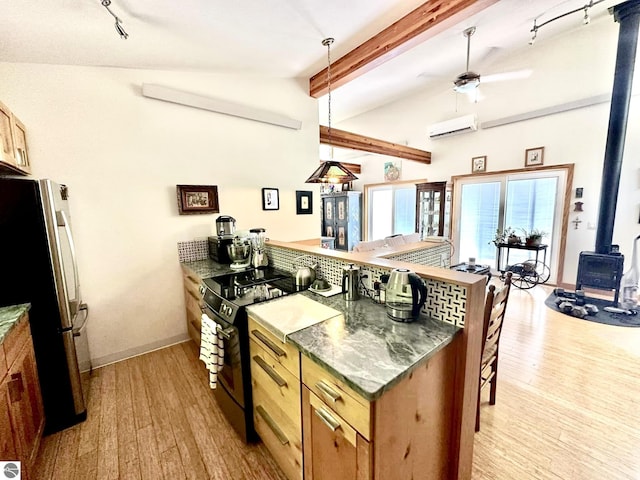 kitchen featuring freestanding refrigerator, a wood stove, black / electric stove, a peninsula, and light wood finished floors