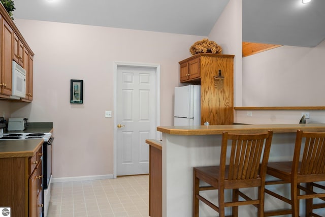 4854 Forest Trl, Bellaire, MI 49615 - kitchen featuring white appliances, brown cabinets, baseboards, a kitchen bar, and light tile patterned floors
