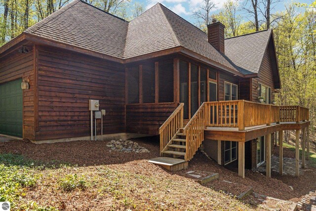 4854 Forest Trl, Bellaire, MI 49615 - rear view of house with roof with shingles, a chimney, stairway, a deck, and a garage