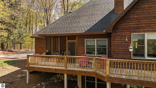 4854 Forest Trl, Bellaire, MI 49615 - back of house featuring a shingled roof, a wooden deck, and a chimney