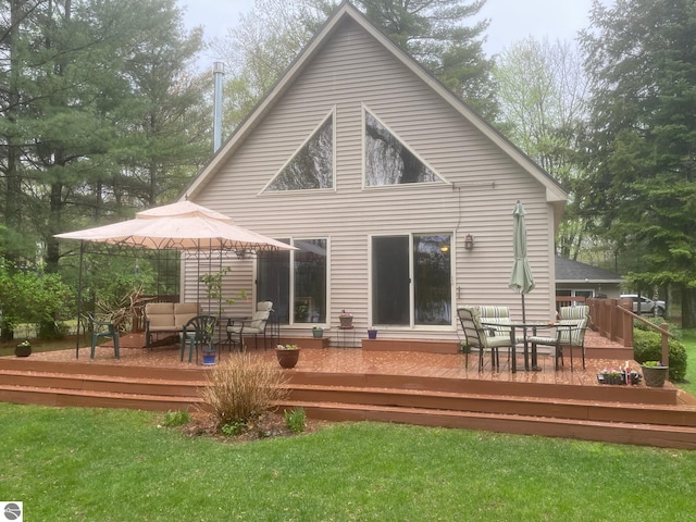 6557 Betsie River Rd, Interlochen, MI 49643 - back of property featuring outdoor dining area, a deck, and a yard