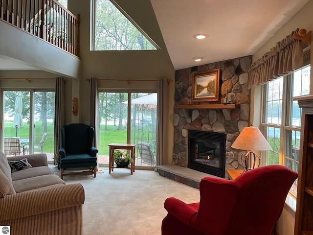 6557 Betsie River Rd, Interlochen, MI 49643 - living room featuring carpet floors, a stone fireplace, and a towering ceiling