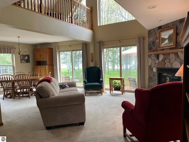 6557 Betsie River Rd, Interlochen, MI 49643 - living area featuring light carpet, a stone fireplace, a towering ceiling, and a chandelier