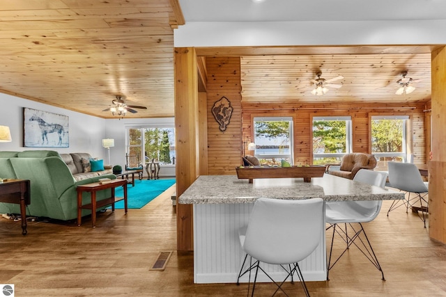 4306 Central Park Dr, Grawn, MI 49637 - kitchen with open floor plan, a ceiling fan, wooden walls, a kitchen breakfast bar, and wooden ceiling