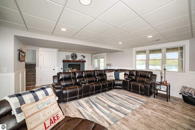 1254 Queensway Dr, Lake Isabella, MI 48893 - living area with a drop ceiling, wainscoting, a brick fireplace, stairway, and wood finished floors
