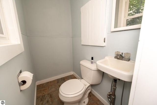 1618 E High, Mount Pleasant, MI 48858 - bathroom featuring toilet, baseboards, stone finish flooring, and a sink