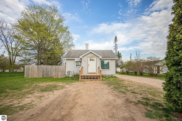 505 S Cherry St, Kalkaska, MI 49646 - bungalow-style home featuring driveway, fence, a chimney, and a shingled roof