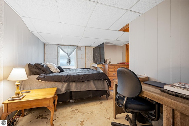 505 S Cherry St, Kalkaska, MI 49646 - bedroom with unfinished concrete flooring, a paneled ceiling, and a decorative wall