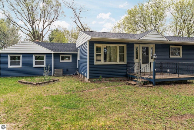 8817 Wilson Rd, Buckley, MI 49620 - view of front facade featuring a front yard, a wooden deck, roof with shingles, and central air condition unit