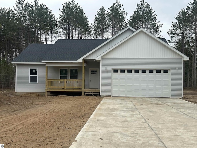 5203 NE Myers Rd, Kalkaska, MI 49646 - view of front of house with covered porch, concrete driveway, an attached garage, and roof with shingles